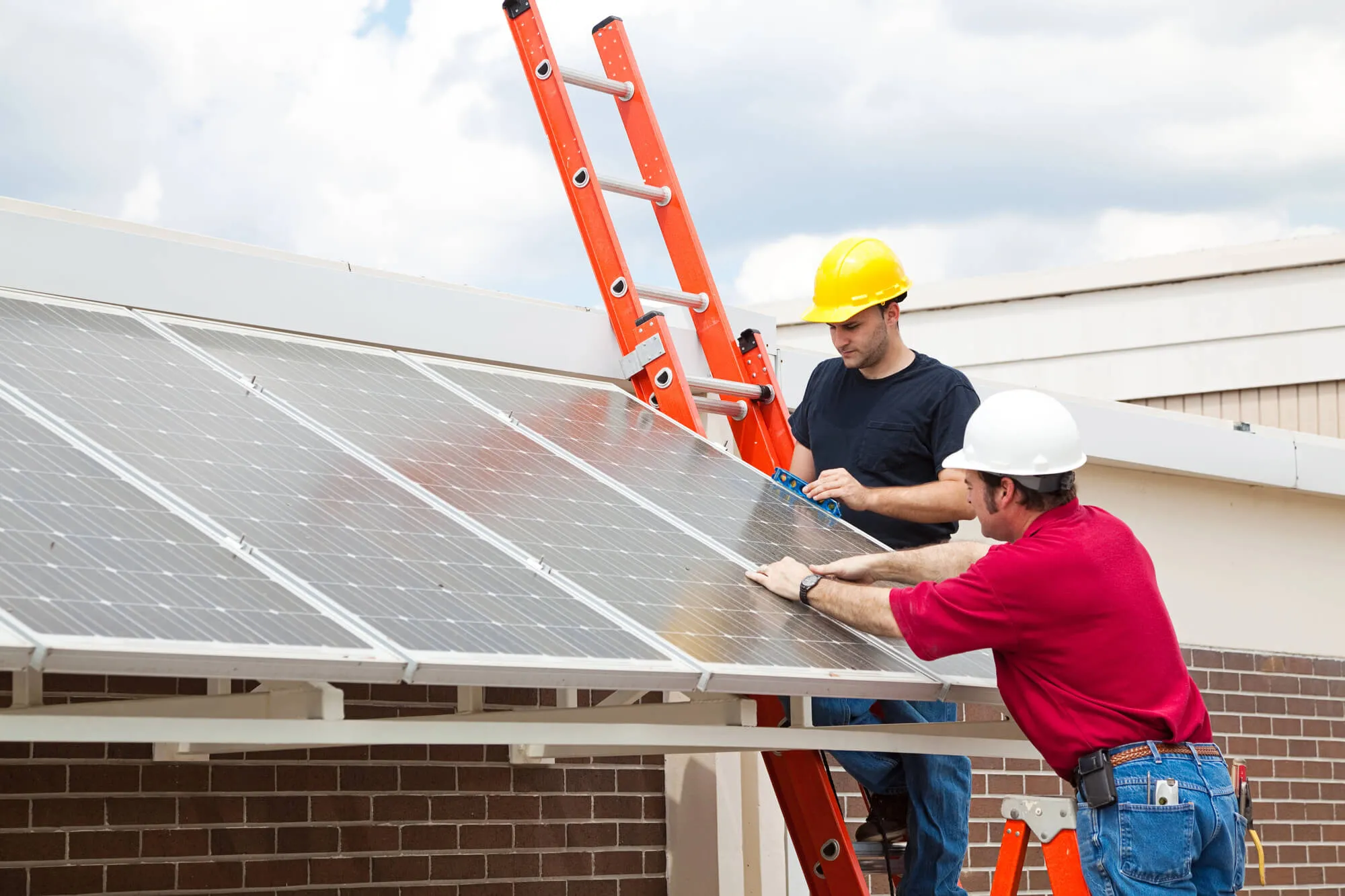 Two solar installers in hard hats mounting solar panels on a building — how to choose a solar installer NC